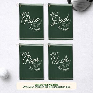 May include: Four dark green golf towels with white text that reads "Best Papa By Par", "Best Dad By Par", "Best Pops By Par", and "Best Uncle By Par". A golf ball and club are also visible.