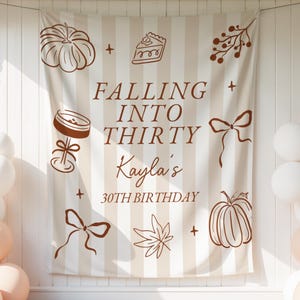 Peut inclure: Une toile de fond en tissu avec des rayures verticales beiges et blanches, ornée d'illustrations au trait marron de citrouilles, d'une part de tarte, de nœuds, d'une feuille et d'un verre à cocktail. Le texte indique : FALLING INTO THIRTY, Kayla's, 30TH BIRTHDAY.