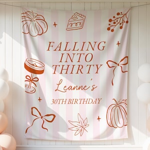 May include: A rectangular fabric backdrop featuring vertical light pink and white stripes with burnt orange line art illustrations of pumpkins, a slice of pie, bows, and leaves. The text reads FALLING INTO THIRTY, Leanne's, 30TH BIRTHDAY.