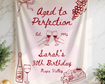 May include: A cream-colored banner with red illustrations and text. The banner reads "Aged to Perfection" with "Est. 1996". It also says "Sarah's 30th Birthday Napa Valley". Wine bottle, glasses, grapes, and cheese board are also illustrated.