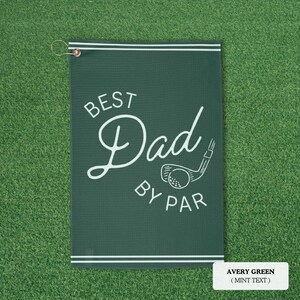May include: Avery green golf towel with the text "BEST Dad BY PAR" in white script and a golf club graphic. The towel has a white border and a metal grommet for hanging.