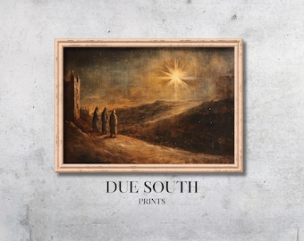 May include: A painting of three figures walking towards a bright star in the distance. The figures are wearing robes and are walking on a path in a desert landscape. The painting is framed in a light wood frame. The text "DUE SOUTH PRINTS" is below the frame.