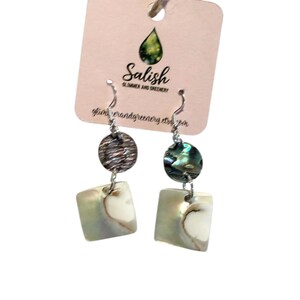 Peut inclure: Boucles d'oreilles pendantes avec crochets argentés, composées d'un dessus rond texturé, d'un ovale nacré et d'un bas carré irisé. Les boucles d'oreilles sont présentées sur une étiquette rose avec le texte "Salish Summer and Greenery".