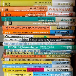 Può includere: Una pila di libri vintage Shell Guide che presentano diverse contee e regioni del Regno Unito. I libri sono gialli, arancioni, blu e verdi con il logo Shell sul dorso.