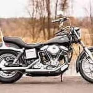 Puede incluir: Una motocicleta Harley Davidson negra con detalles cromados. La motocicleta tiene un asiento individual y un respaldo.