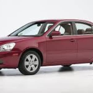 Può includere: Una berlina bordeaux con ruote argentate e vetri oscurati. L'auto ha un design elegante con una griglia anteriore e fari. Il veicolo è parcheggiato su una superficie bianca.