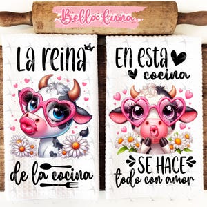 May include: Two white kitchen towels with a cow cartoon design. The first towel says "La reina de la cocina" and the second towel says "En esta cocina se hace todo con amor".