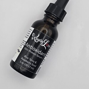 May include: A dark brown glass bottle with a black dropper top, labelled "Antioxidant (Skin Protect Serum)" with the brand name "Kaylee Love" and the text "Blue Tansy & Raspberry Seed 1 oz (29.57 ml)".