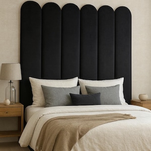 May include: A bedroom scene featuring a black, arched headboard, a bed with neutral-toned bedding, and decorative pillows in shades of gray and white. A tan throw blanket adds warmth. A wooden nightstand with a lamp is on the left.