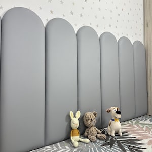 May include: A series of six vertical, light gray, arched wall panels arranged side-by-side. The panels feature a smooth, matte finish and rounded tops, creating a continuous, repetitive shape along the wall surface in a bedroom setting.