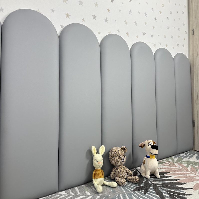 May include: A series of six vertical, light gray, arched wall panels arranged side-by-side. The panels feature a smooth, matte finish and rounded tops, creating a continuous, repetitive shape along the wall surface in a bedroom setting.
