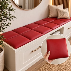Peut inclure: Un banc de rangement blanc doté d'un coussin supérieur composé de plusieurs panneaux carrés rouge foncé à la texture lisse. Le banc comprend un tiroir avec une poignée dorée et une étagère ouverte. Un encart circulaire montre un panneau rouge.