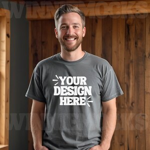 Może przedstawiać: Mężczyzna w szarej koszulce z nadrukiem "YOUR DESIGN HERE" w kolorze białym.