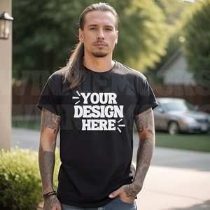 May include: A man wearing a black t-shirt with the text "YOUR DESIGN HERE" printed in white. He is standing outdoors with a car in the background.
