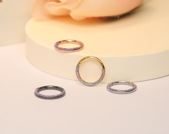 Puede incluir: Cuatro aros de aro sin costuras de diferentes colores con incrustaciones de ópalo. Los aros son de oro, oro rosa, plata y negro.