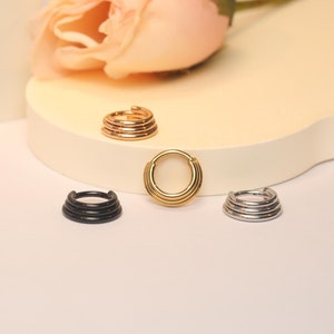May include: Four different colored hoop earrings with multiple rings. The earrings are gold, silver, and black.
