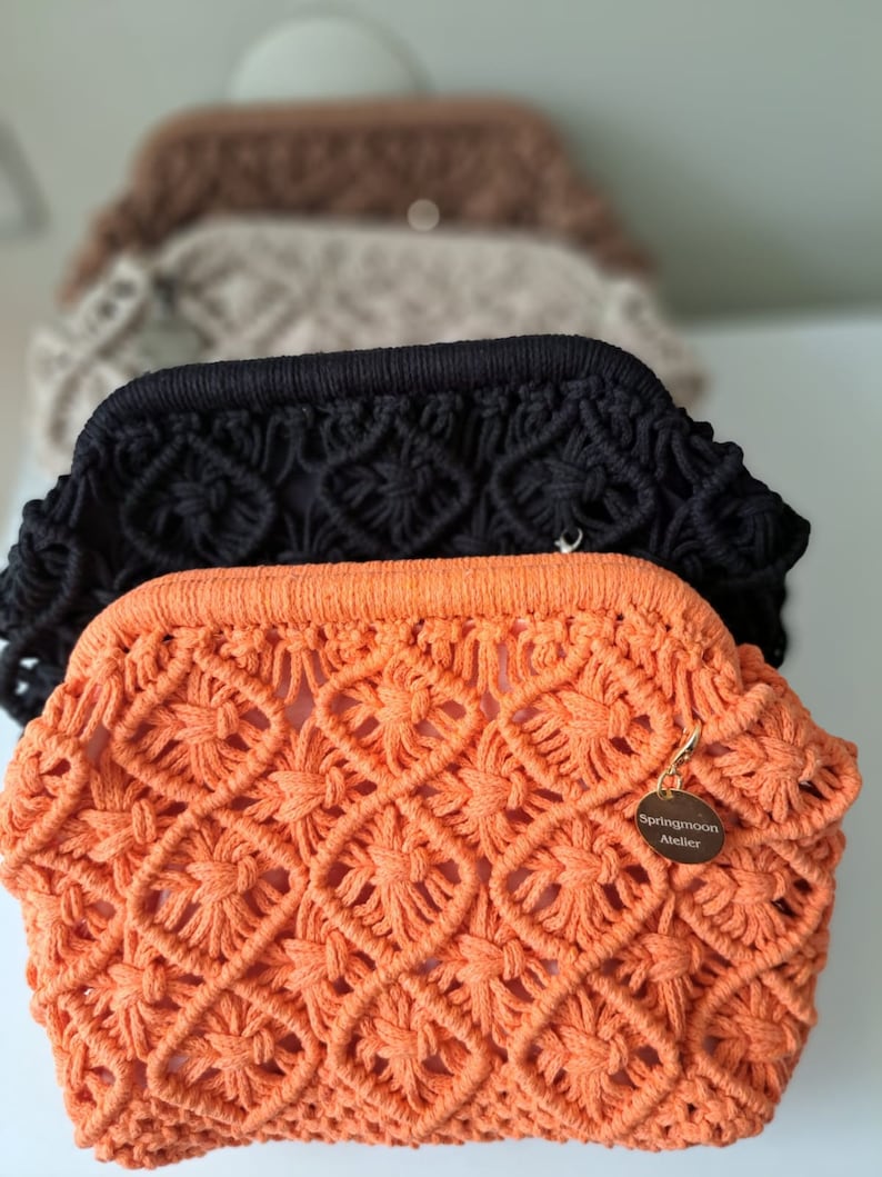 Op de afbeelding: Oranje gebreide clutch met een gouden label met de tekst "Springmoon Atelier".