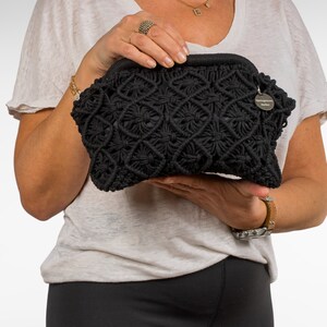Op de afbeelding: Zwarte gecrochete clutch met een klein rond label met de tekst "Springblossom Malibu".
