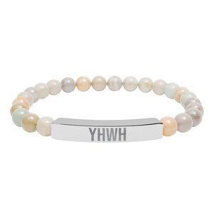 Könnte beinhalten: Ein Armband mit pastellfarbenen Perlen und einem silbernen Steg. Der Steg ist mit den Buchstaben "YHWH" graviert. Die Perlen sind in Creme-, Grau- und Pfirsichtönen gehalten. Ein stilvolles Accessoire.