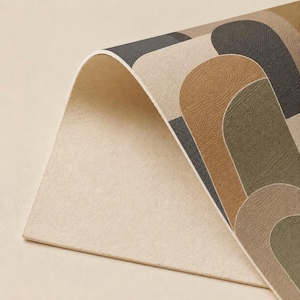 May include: A curved sheet of material featuring a repeating pattern of rounded arch shapes in shades of dark gray, tan, brown, and olive green. The underside of the sheet is a solid, light beige color with a textured, matte surface finish.