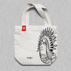 May include: White tote bag with black and white line art of a woman's face with a sunburst behind her. The text "SumiRyu Studio" is printed on the bag.