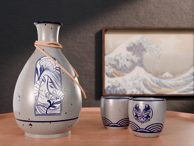 May include: A gray ceramic sake set with a floral design on the bottle and a wave design on the cups. The set includes a bottle, two cups, and a rope.