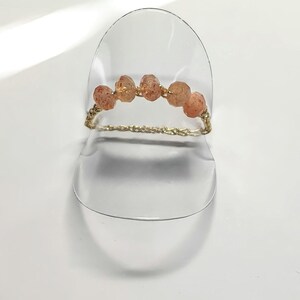 Op de afbeelding: Een gouden kettingring met vijf oranje sunstone kralen.