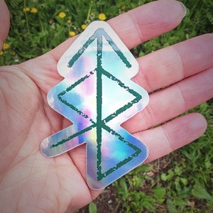 Può includere: Un adesivo olografico con un contorno verde di un simbolo di albero. L'adesivo ha uno sfondo arcobaleno iridescente.