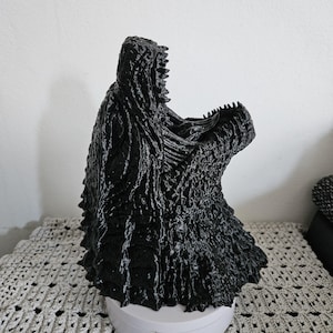 May include: A black 3D printed model of a monster's head with a large open mouth and detailed textured skin.