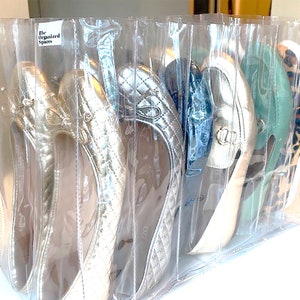 May include: Clear plastic shoe storage bags with a label that reads "The Organized Spares". The bags contain a variety of shoes, including gold, silver, and green shoes.