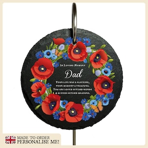 May include: A black slate memorial plaque with a floral wreath of red poppies and blue flowers. The plaque has the text "In Loving Memory Dad Your life was a blessing, your memory a treasure, You are loved beyond words & missed beyond measure."