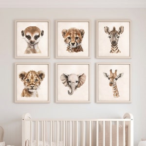 May include: Six framed watercolor prints of safari animals, including a meerkat, cheetah, zebra, lion cub, elephant, and giraffe. The prints are in neutral tones and are displayed above a white crib in a nursery setting.