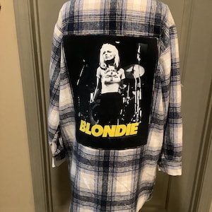 May include: Plaid flannel shirt in blue, white, and cream. A large black patch on the back features a black and white image of Blondie's lead singer, Debbie Harry, with the band's name in yellow.