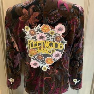 May include: A black velvet jacket with a paisley print and a floral patch featuring the text "Fleetwood Mac".