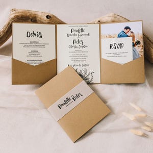 May include: A tri-fold kraft paper wedding invitation suite featuring a central panel with black text, a left pocket for details, and a right pocket holding an RSVP card. A matching kraft paper belly band with the names Paulette and Peter is included.