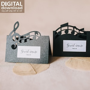 Peut inclure: Deux marque-places en papier cartonné noir pailleté avec des motifs musicaux découpés au laser. L'un présente une clé de sol et une portée, l'autre des notes de musique. Chaque carte porte une étiquette blanche avec le texte Guest name TABLE N.