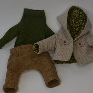 A green sweater and a beige jacket with a patterned lining are laid out on a white background.