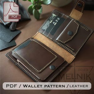 May include: A brown leather bifold wallet featuring visible light-colored stitching, a snap-button coin pocket, multiple card slots, and a snap-button closure strap. The wallet is displayed open, revealing its interior compartments and construction.