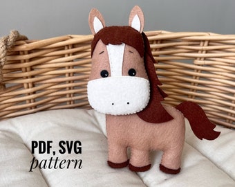 May include: A handmade felt horse toy in shades of brown, tan, and white. The horse has a long, flowing mane and tail, with the text "PDF, SVG pattern" in black. The toy is designed to stand upright.