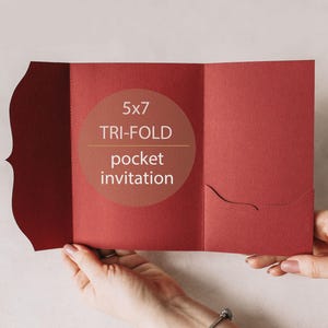 May include: A deep red tri-fold pocket invitation with a decorative scalloped edge on the left flap and a curved pocket on the right panel. The center panel features the text 5x7 TRI-FOLD pocket invitation printed in a light color.