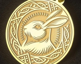 May include: A gold pendant necklace with a circular design featuring a white rabbit head with intricate details. The rabbit is surrounded by a decorative border of leaves and vines.