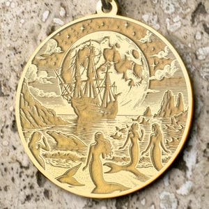 以下が含まれることがあります： 満月のもとを航海する船と、水の中で泳ぐ3人の人魚が彫刻された、金のペンダントネックレス。