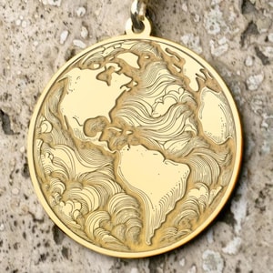 Könnte beinhalten: Eine goldfarbene Halskette mit Anhänger, die eine detaillierte Weltkarte zeigt. Der runde Anhänger hängt an einer filigranen Kette. Die Kontinente sind aufwendig geätzt und zeigen die Landmassen der Erde.