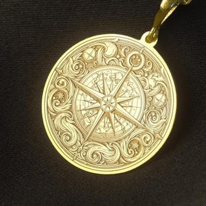 Peut inclure: Un collier pendentif doré avec un motif de rose des vents détaillé. Le pendentif rond est gravé de manière complexe avec une rose des vents, des étoiles et des motifs tourbillonnants. Le collier a une chaîne délicate et un fermoir.