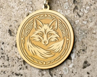 Op de afbeelding: Goudkleurige hangerketting met een gedetailleerd vossendesign. De ronde hanger toont de kop en staart van een vos binnen een decoratieve rand. De ketting heeft een fijne ketting en wordt gepresenteerd tegen een getextureerde, neutrale achtergrond.