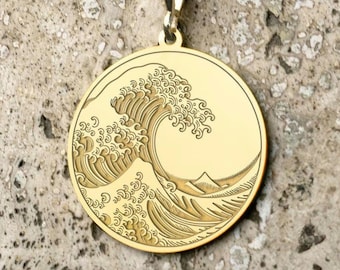 May include: A gold necklace with a round pendant featuring an engraved image of the Great Wave off Kanagawa, a famous Japanese woodblock print by Hokusai.