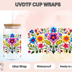 May include: A clear glass tumbler with a wooden lid and a straw. The tumbler is decorated with a colorful floral pattern. The text "UVDTFC CUP WRAPS" is at the top of the image. The text "16oz Wrap", "Waterproof", and "Ready to Apply" are at the bottom of the image.