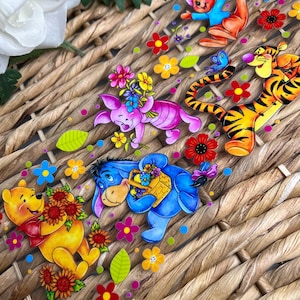 May include: A set of colorful Winnie the Pooh character stickers with floral accents. The stickers feature Winnie the Pooh, Tigger, Piglet, Eeyore, and Roo. The stickers are perfect for adding a touch of whimsy to any project.
