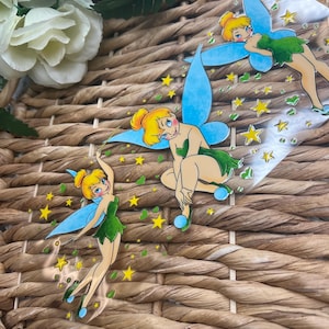 May include: Three clear sticker sheets with images of Tinkerbell, the fairy from Disney's Peter Pan. Each sticker features Tinkerbell with her signature blue wings and green dress, surrounded by yellow stars and green hearts.