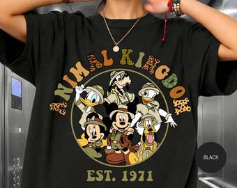 Peut inclure: Un t-shirt noir avec un motif circulaire représentant des personnages de dessins animés en tenue de safari. Le texte ANIMAL KINGDOM est arqué au-dessus en lettres à motifs, avec EST. 1971 en dessous. Mickey, Minnie, Donald, Daisy, Dingo et Pluto.